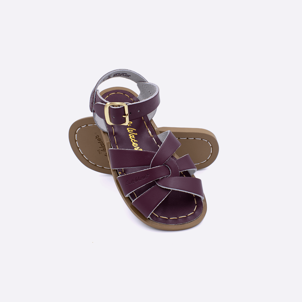 Two toddler sized 800 Original style sandals with claret straps and claret insoles.  One standing with the sole facing the camera. The second is laying diagonally over the top left edge of the sole.